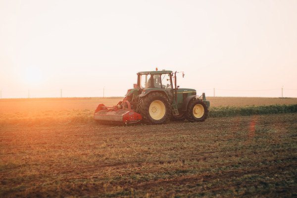 A tractor working in a field at sunset
