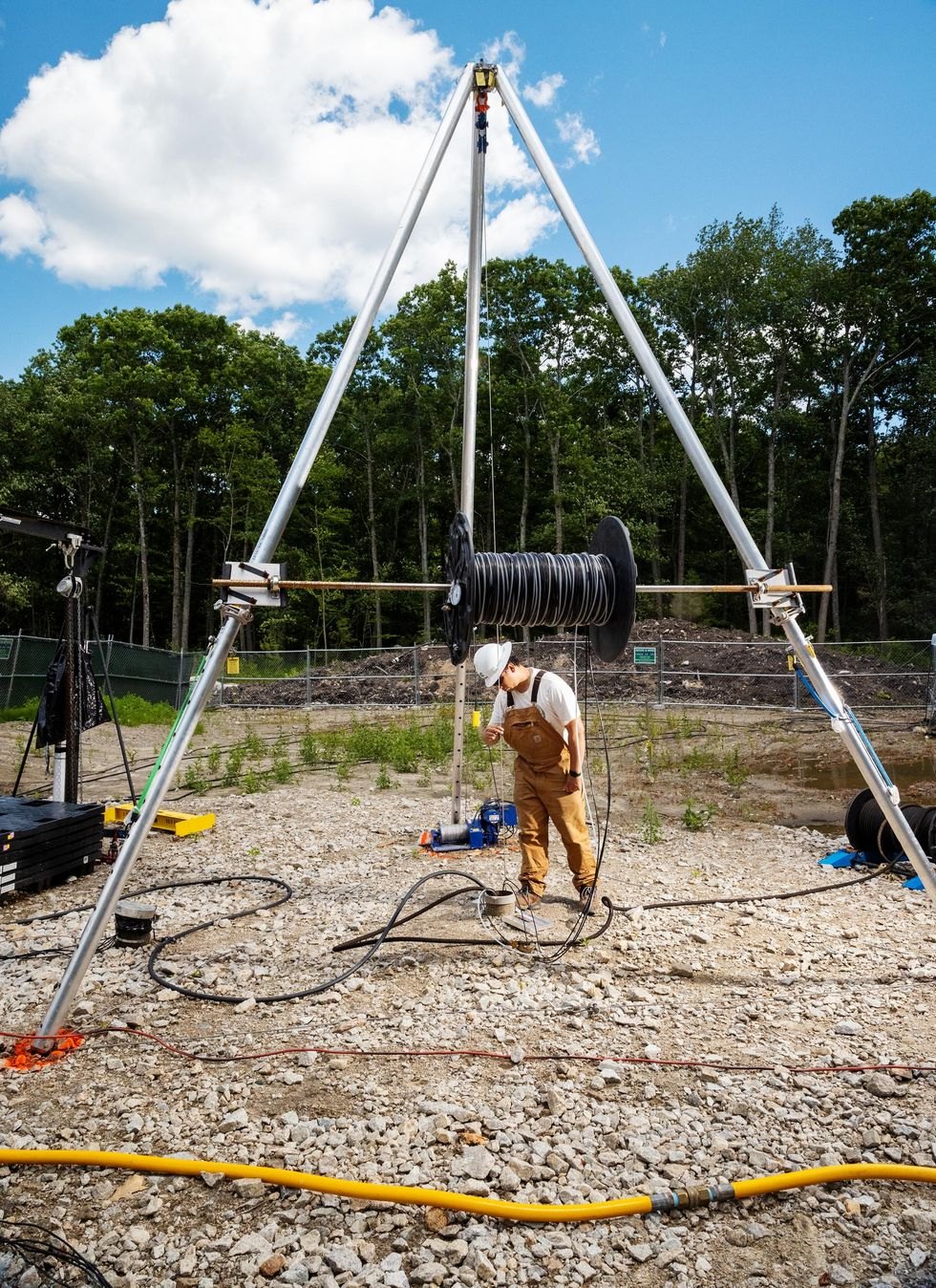 A worker guiding equipment into a well at an outdoor test site
