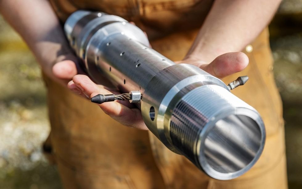 Hands holding a cylindrical component of a downhole electrode