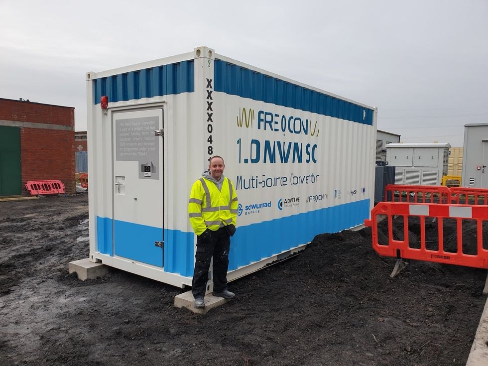 A containerised energy-storage installation with a person in a high-visibility jacket