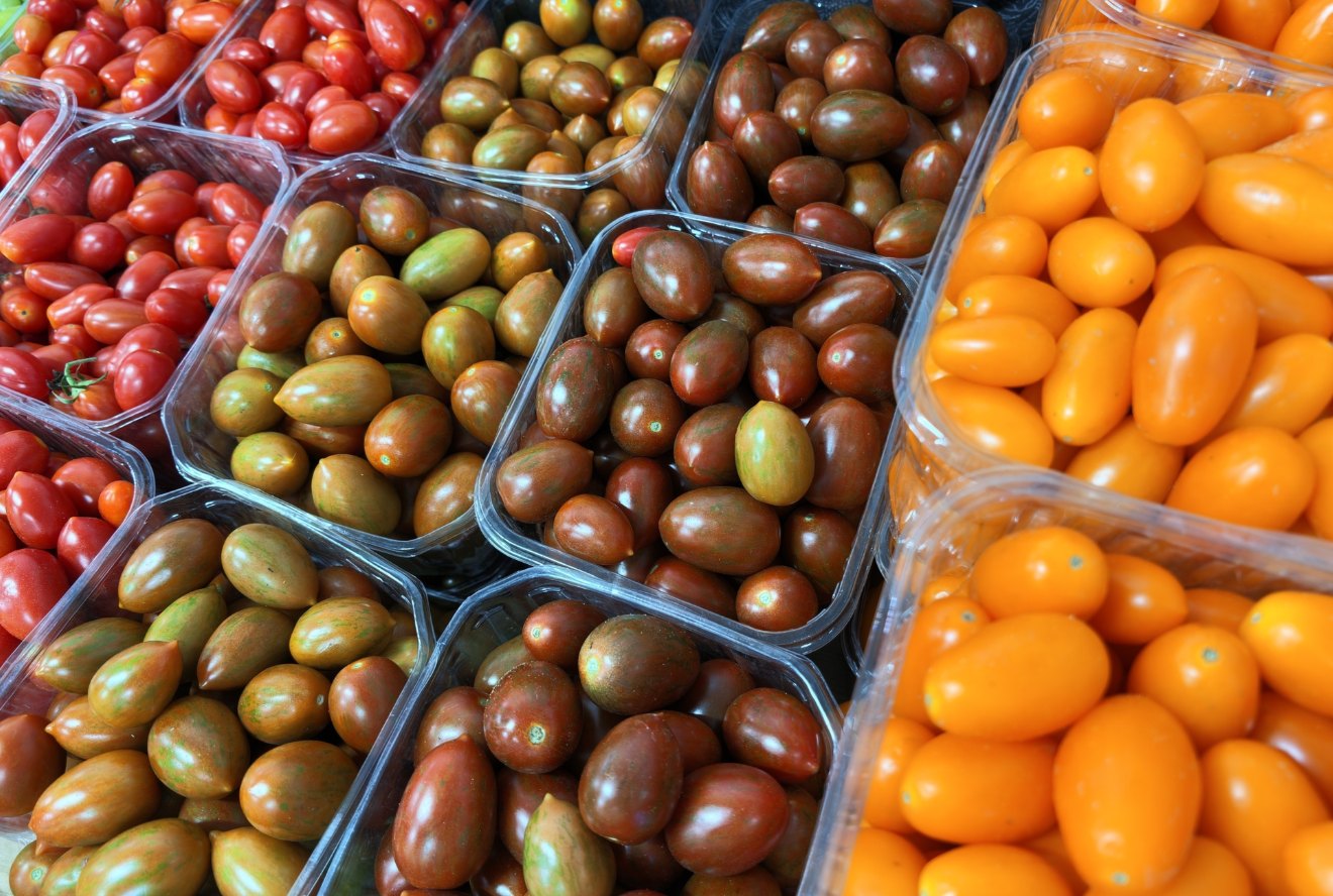 Red, green and yellow cherry tomatoes arranged in market containers