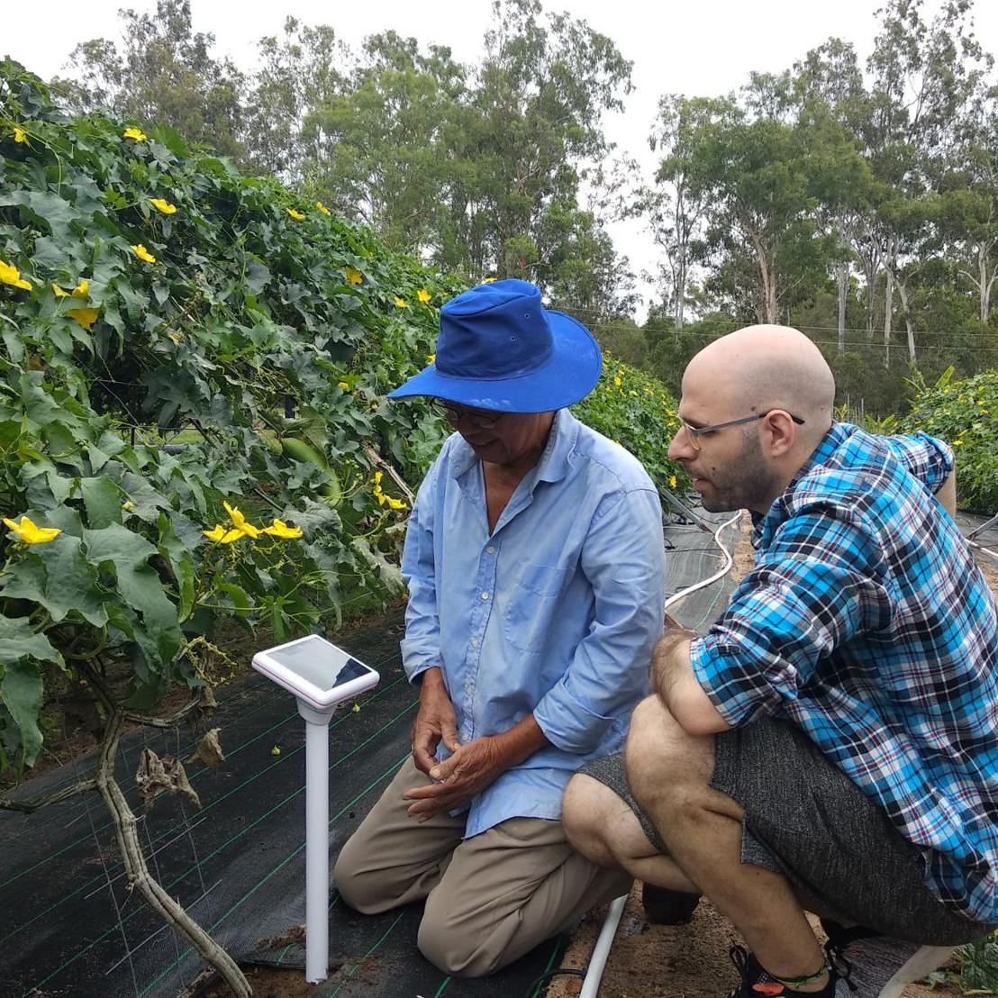 Dos personas junto a un sensor de suelo en una parcela cultivada